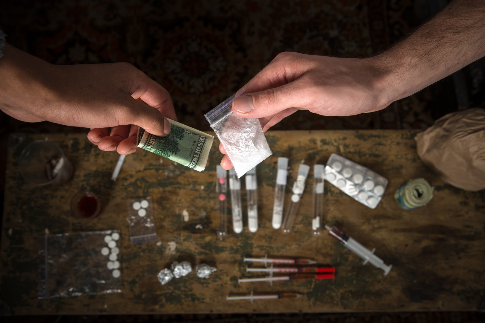 רכישה, החזקה ומכירה של סמים ניתנות לעונש על פי חוק. סוגים רבים של סמים וסמים מיוצגים על השולחן.